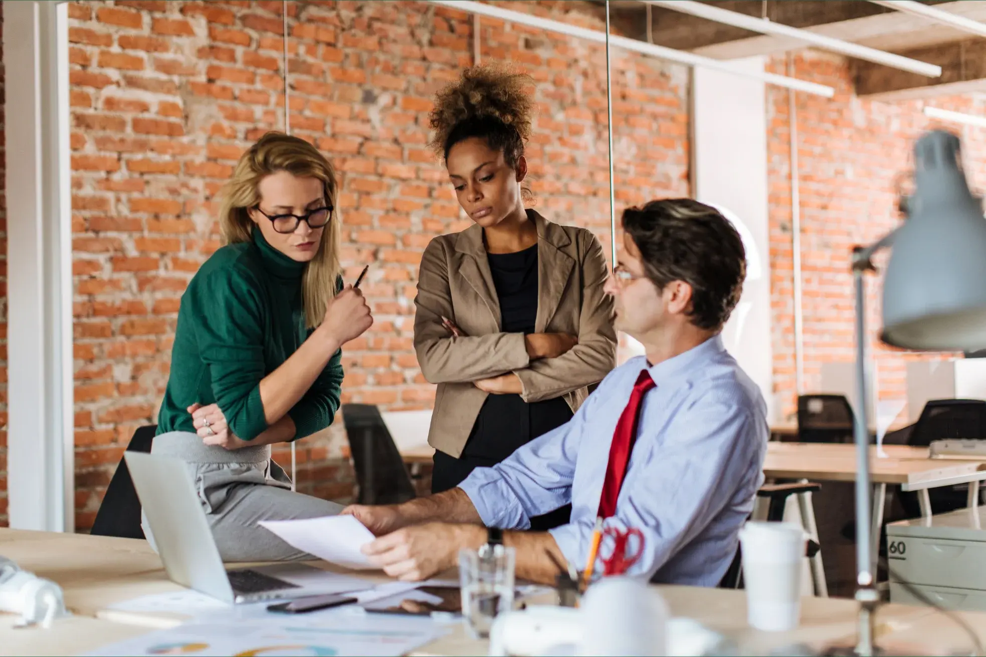 Three finance professionals reviewing printed financial statements together before a lender submission