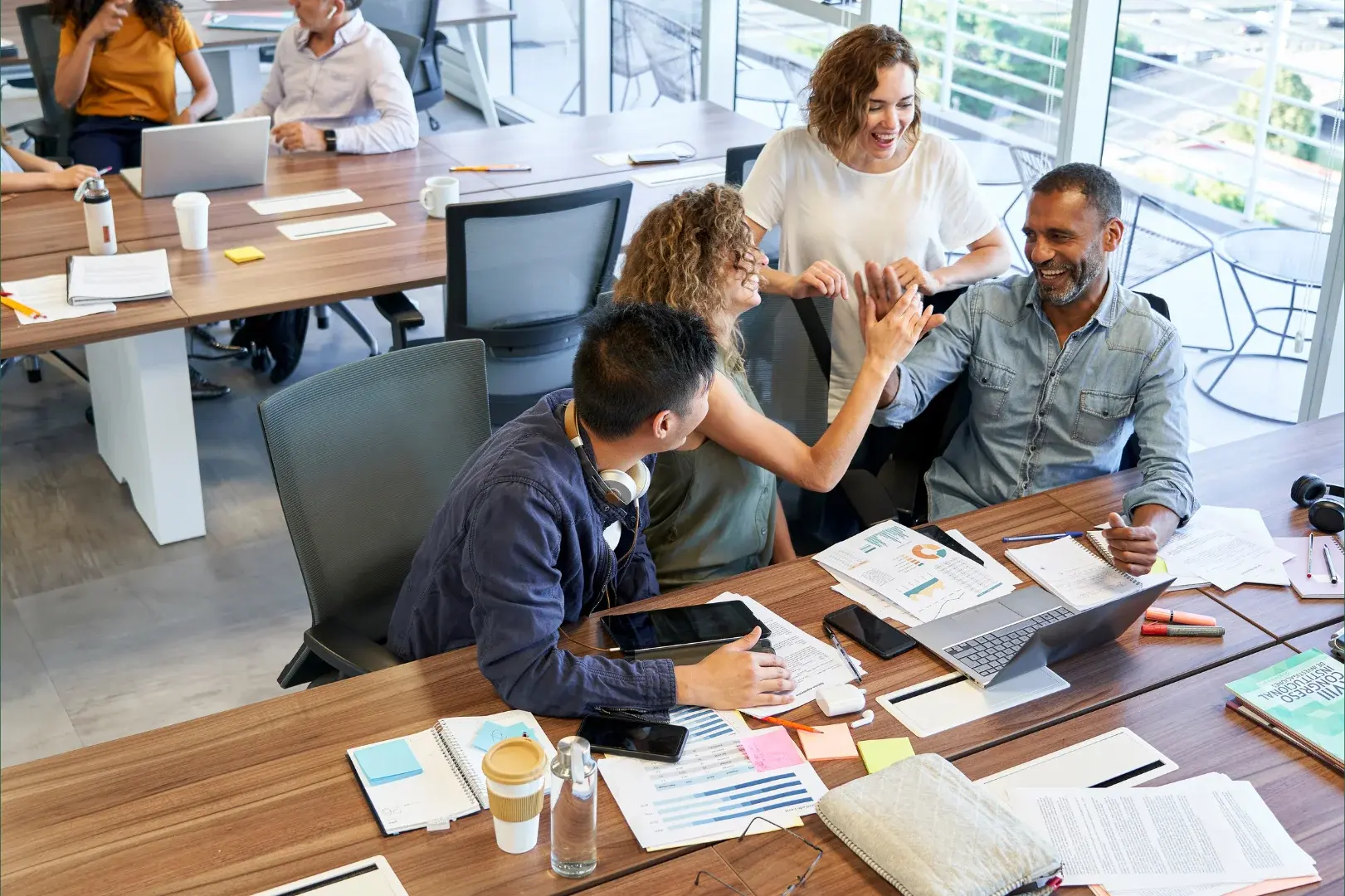 Startup team celebrating growth around a table of charts and financial reports